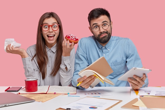 Mitarbeiter sitzen am Schreibtisch mit Dokumenten und Geräten