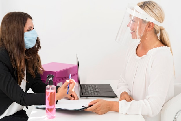 Mitarbeiter tragen medizinische Maske und Gesichtsschutz