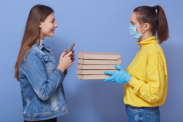 Mitarbeiterin der Lieferung in gelbem Hemd, Maske und Handschuhen