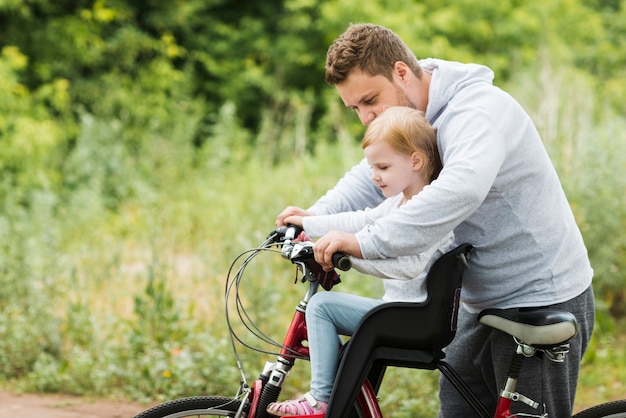 Mitfühlender Vater, der Tochter auf Fahrrad hält