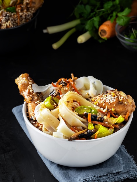 Mittagessen nach asiatischer Art mit Nudeln mit Hühnchen in Teriyaki-Sauce, Gemüse, Gewürzen und Microgreens