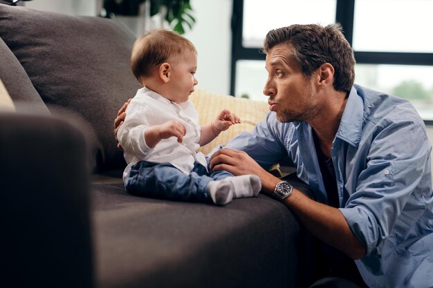 Mitte erwachsener Vater, der sich mit seinem kleinen Sohn verbindet und mit ihm im Wohnzimmer spricht