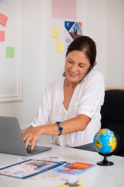 Kostenloses Foto mittelgroße frau, die im reisebüro arbeitet