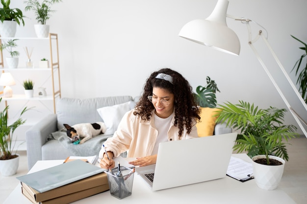 Mittelgroße Frau, die mit Laptop am Schreibtisch arbeitet