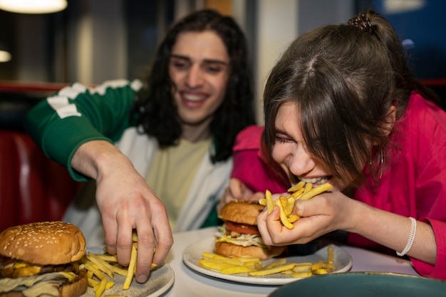 Kostenloses Foto mittelgroße freunde, die auf lustige weise fast food essen