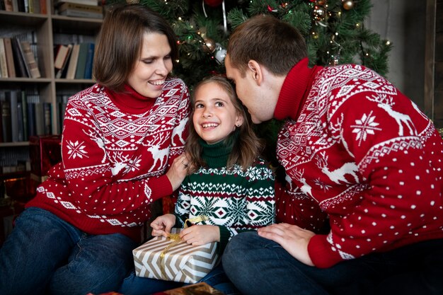 Mittelgroße glückliche Familie mit Geschenk