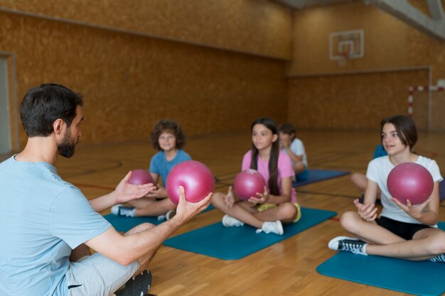 Mittelgroße Kinder auf Yogamatten mit rosa Bällen