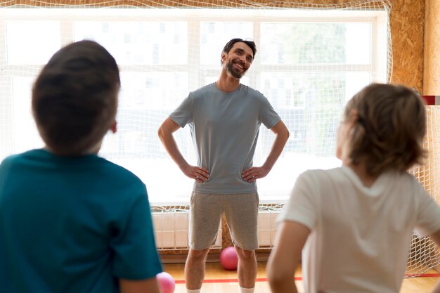 Mittelgroße Kinder in der Turnhalle mit Lehrer