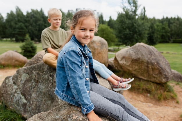 Mittelgroße Kinder sitzen auf Felsen