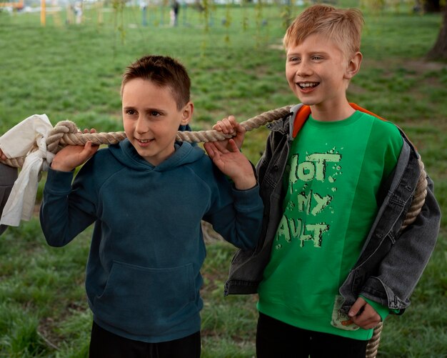 Mittelgroße Kinder spielen im Park Tauziehen