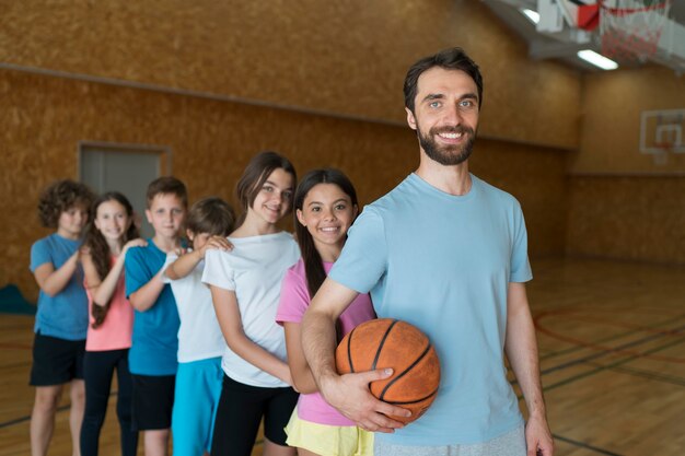 Mittelgroße Kinder und Lehrer mit Basketball