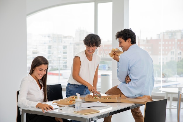 Mittelgroße Leute, die bei der Arbeit Pizza essen