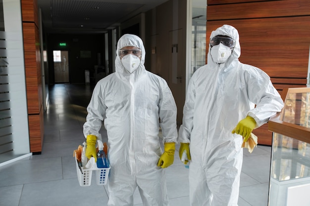 Mittelgroße Leute, die in Hazmat-Anzügen putzen