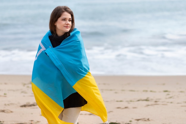 Mittelgroße Smiley-Frau mit ukrainischer Flagge am Strand