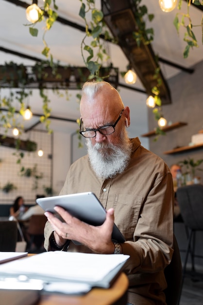 Mittelgroßer älterer Mann, der mit Gerät studiert