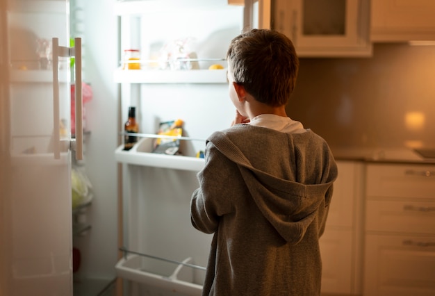 Mittelgroßer Junge, der in den Kühlschrank schaut