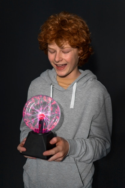 Kostenloses Foto mittelgroßer junge interagiert mit einer plasmakugel