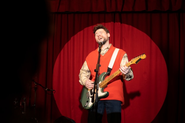 Kostenloses Foto mittelgroßer mann, der auf der bühne singt