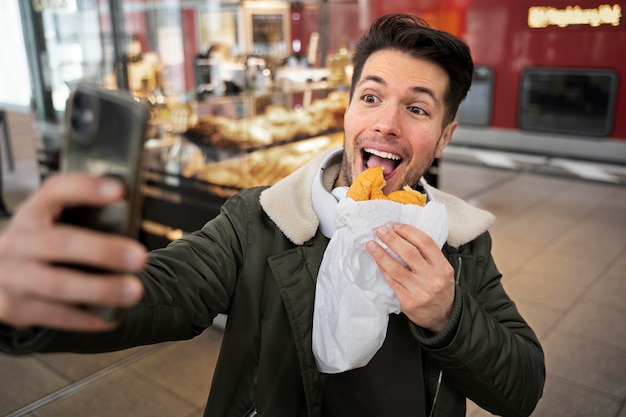 Kostenloses Foto mittelgroßer mann, der selfie mit essen macht