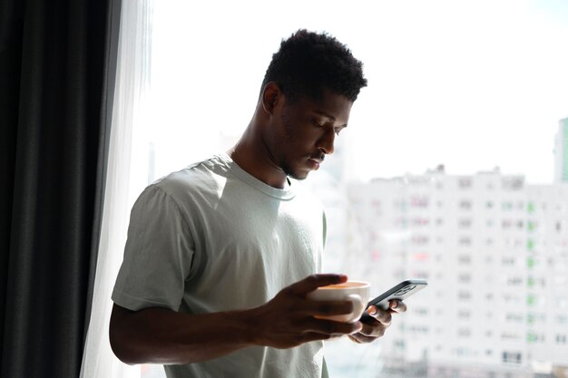 Mittelgroßer Mann mit Telefon und Tasse