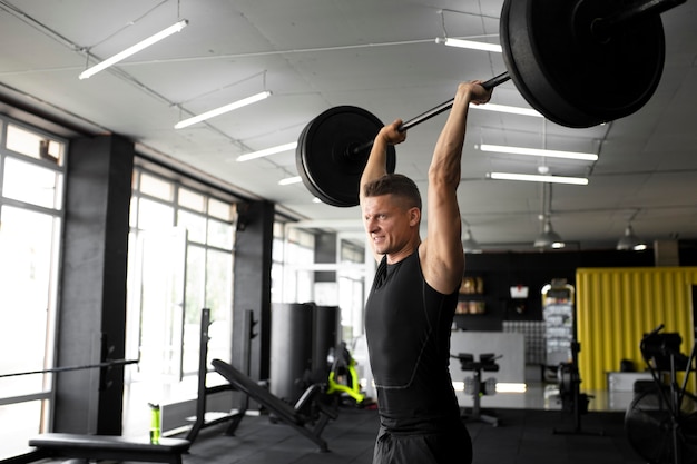 Kostenloses Foto mittelgroßer mann trainiert im fitnessstudio