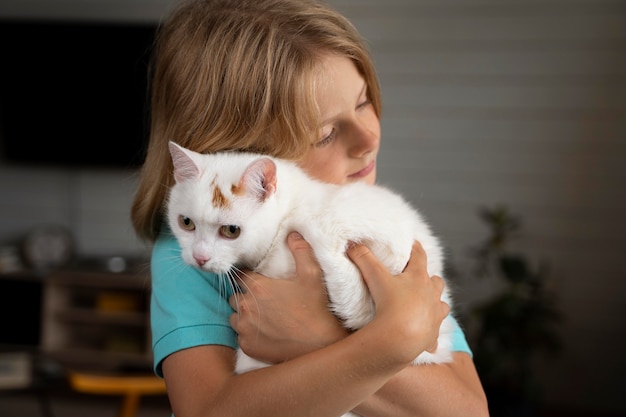 Mittelgroßes Kind umarmt Katze