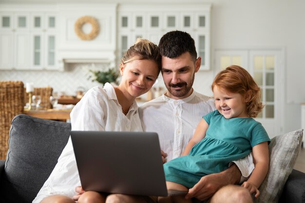 Mittelgroßes Kind und Eltern mit Laptop