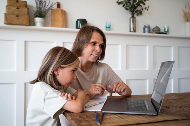 Mittelgroßes Kind und Frau mit Laptop