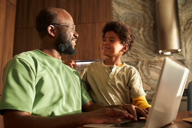 Mittelgroßes Kind und Vater mit Laptop