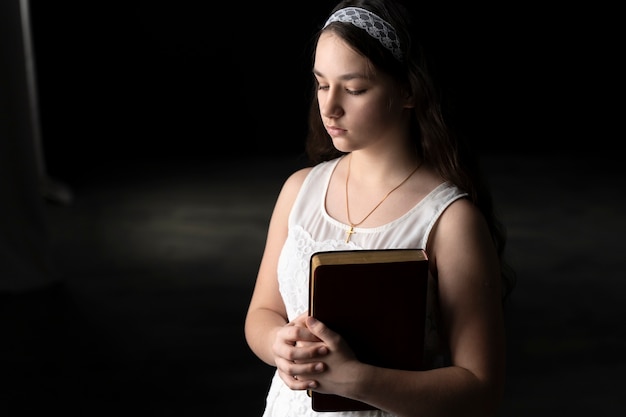 Mittelgroßes Mädchen betet mit einer Bibel