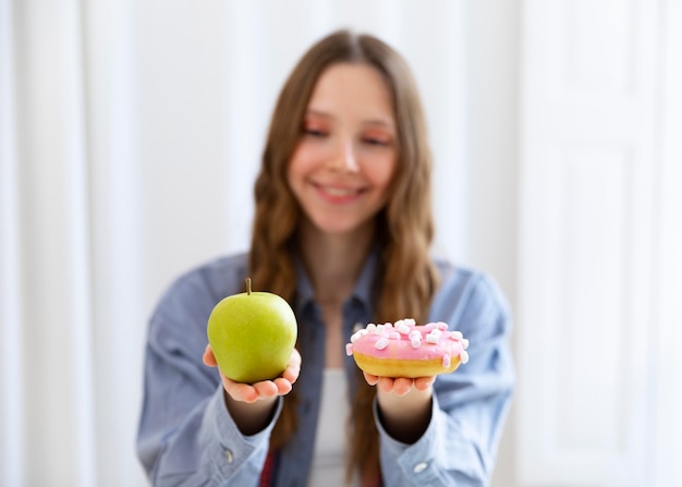 Mittelhohe Frau mit Donut und Apfel