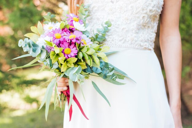 Mittelteil der Hand einer Braut, die Blumenblumenstrauß hält