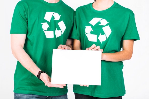 Kostenloses Foto mittelteilansicht der hand des mannes und der frau, die leeres weißes plakat hält