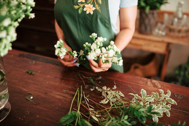 Mittelteilansicht der Hand einer Frau, die Bündel weiße Blumen hält