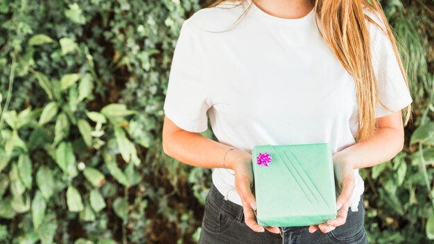 Mittelteilansicht der Hand einer Frau, die grüne Geschenkbox hält