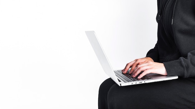 Kostenloses Foto mittelteilansicht der hand einer person unter verwendung des laptops auf weißem hintergrund