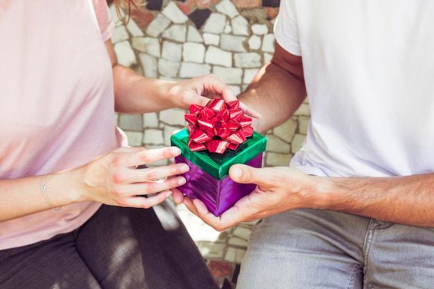 Mittelteilansicht der Hand eines Paares, die Geschenkbox hält