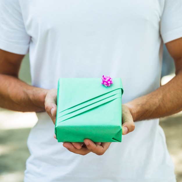 Mittelteilansicht die Hand eines Mannes, die grüne Geschenkbox hält