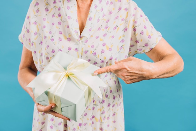 Mittelteilansicht einer Frau, die auf Geburtstagsgeschenk zeigt