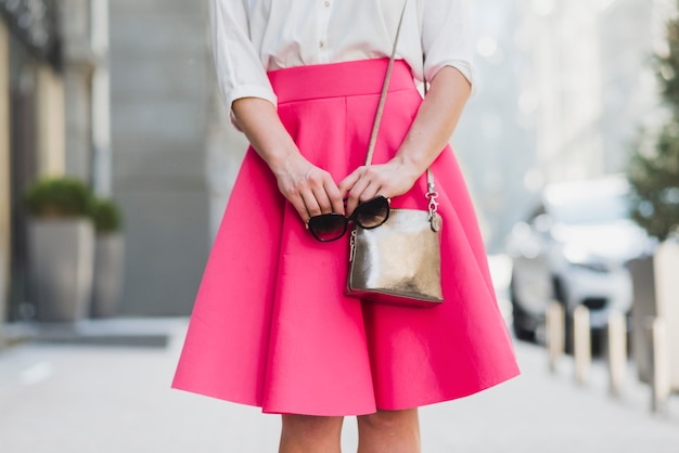 Mittelteilansicht einer Frau mit Sonnenbrille und Handtasche