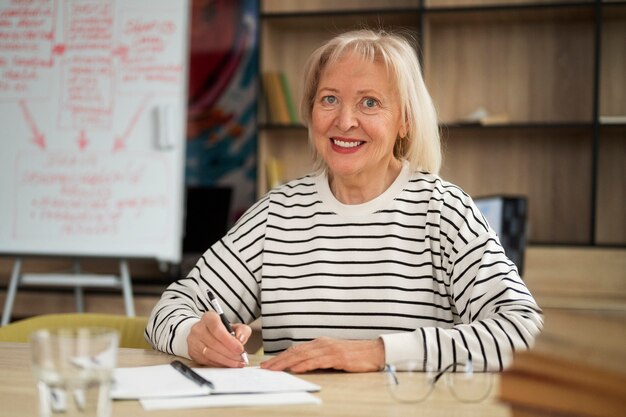 Mittlere Aufnahme ältere Frau, die im Klassenzimmer studiert