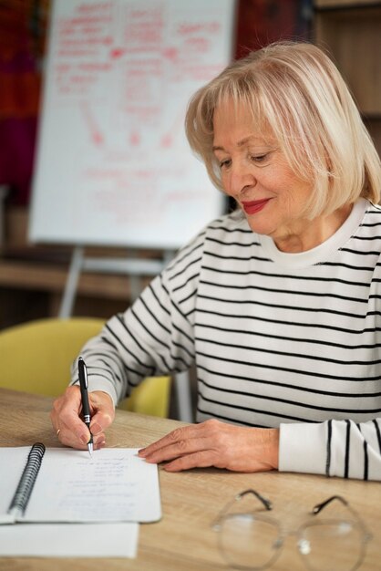 Mittlere Aufnahme ältere Frau, die im Klassenzimmer studiert