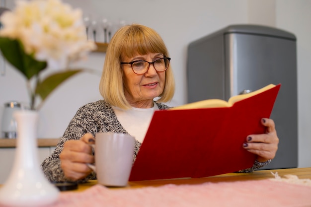 Mittlere Aufnahme alte Frau, die zu Hause liest