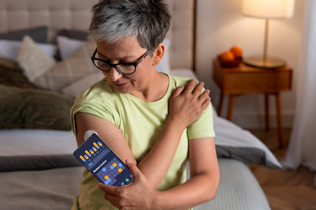 Kostenloses Foto mittlere aufnahme einer diabetikerin, die ihren glukosespiegel überprüft