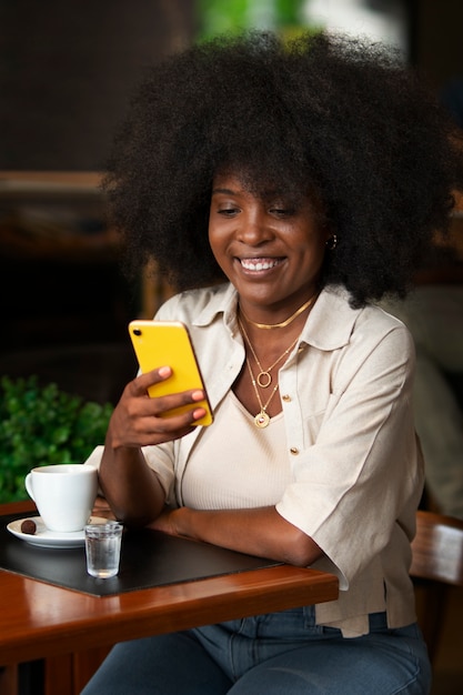 Mittlere Aufnahme einer Frau, die eine Zeitschrift auf dem Smartphone liest