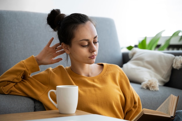 Mittlere Aufnahme einer Frau, die im Wohnzimmer liest