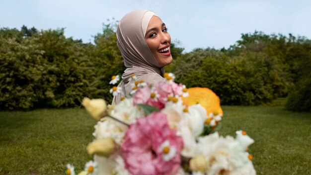 Mittlere Aufnahme einer muslimischen Frau, die mit Blumen posiert