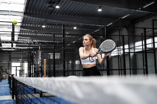 Mittlere Aufnahme fitte Frau, die Paddle-Tennis spielt