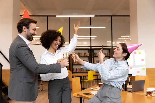 Kostenloses Foto mittlere aufnahme glückliche menschen, die bei der arbeit feiern