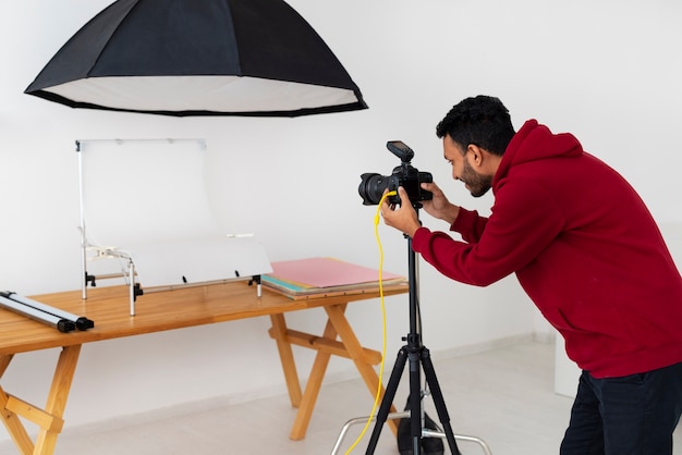 Kostenloses Foto mittlere aufnahme spezialisierter fotograf, der im studio arbeitet